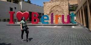 Liban : une femme portant un masque passe devant un signe "j'aime Beyrouth" alors que les autorités ont imposé un nouveau confinement de deux semaines pour limiter la propagation du coronavirus