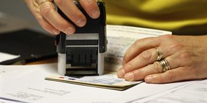 Un employé valide une extension de visa étudiant pour un passeport dans un bureau étranger à Paris. Novembre 2011