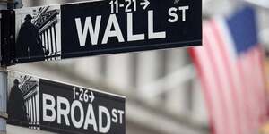 Un panneau wall street est suspendu devant un drapeau americain a l'exterieur de la bourse de new york